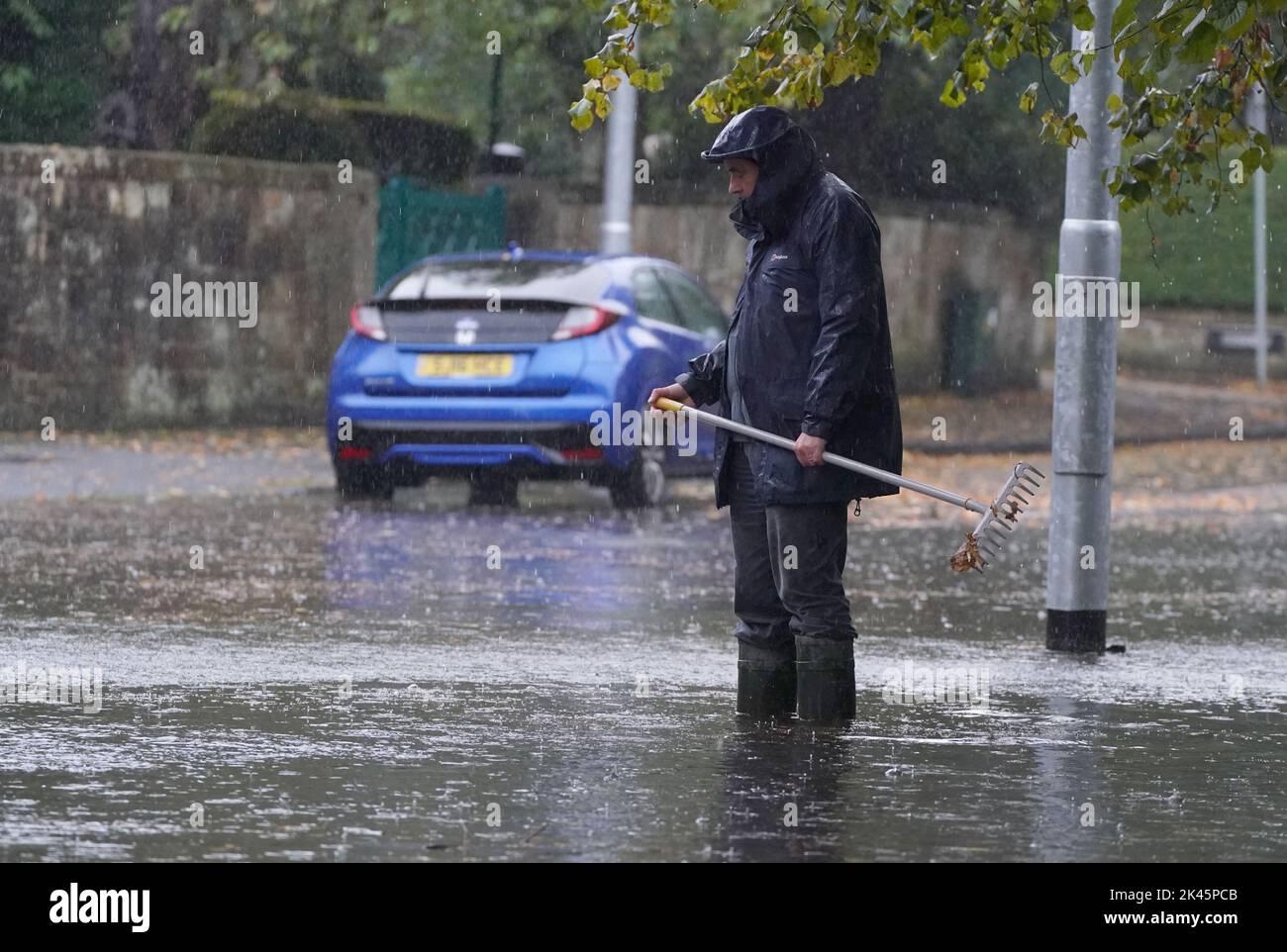 A man tries to ease flooding by clearing autumnal debris from the