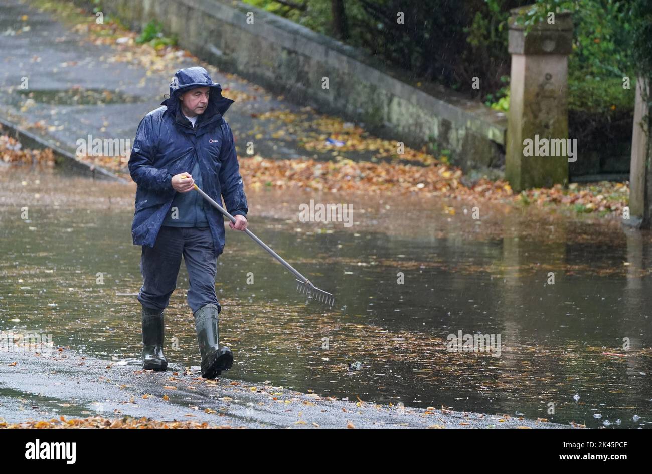 A man tries to ease flooding by clearing autumnal debris from the