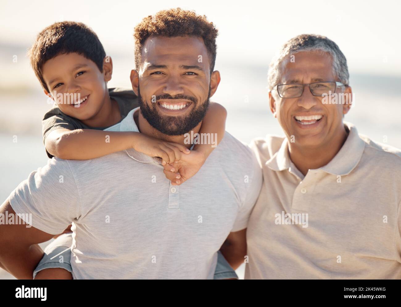 Happy outdoor adventure, portrait of family on beach in Rio de Janeiro and generations of men travel together. Young boy child on fathers back, dad Stock Photo