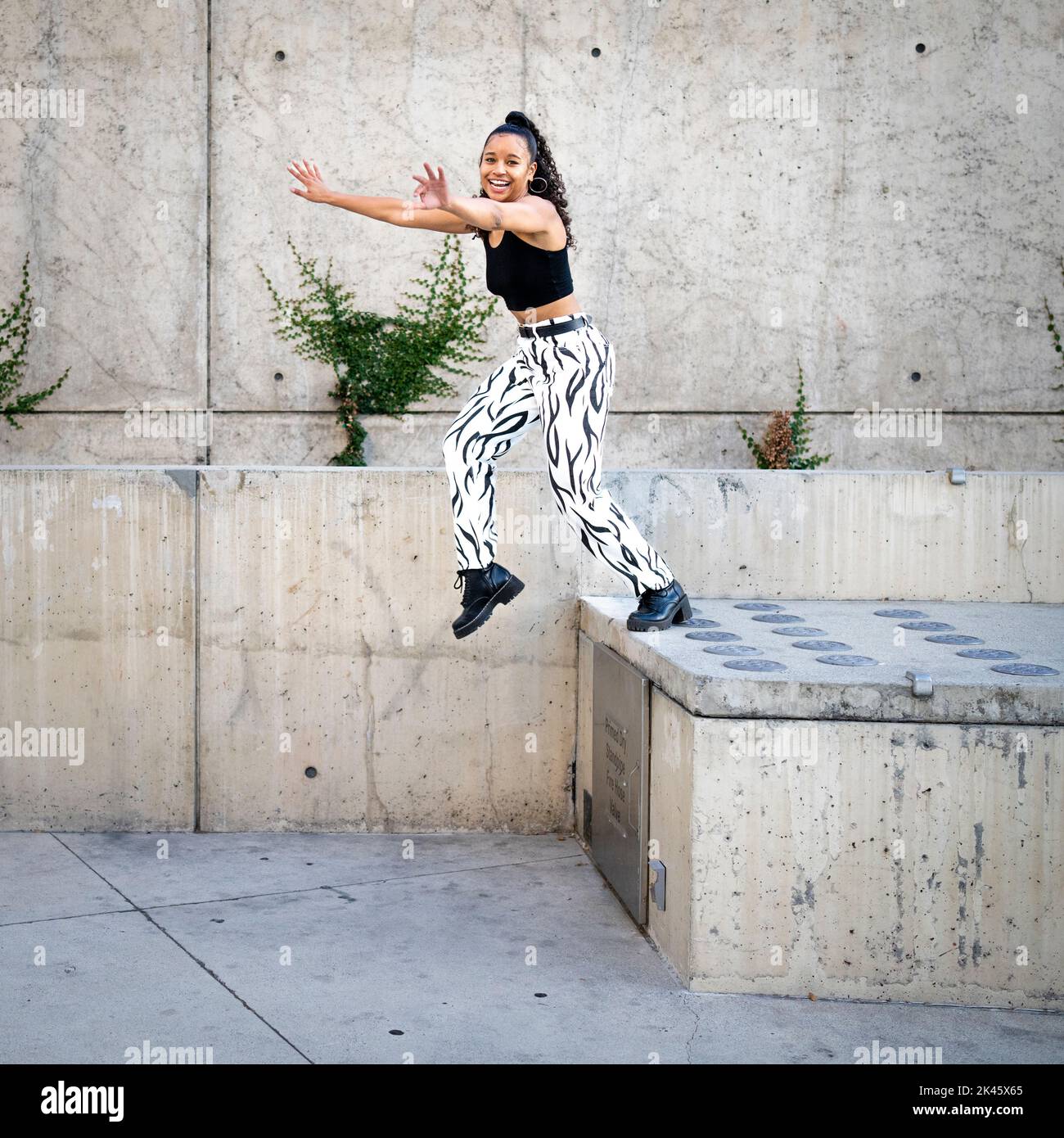 Sequence of Shots of Happy Young Black Woman Jumping Off a Walkway Stock Photo