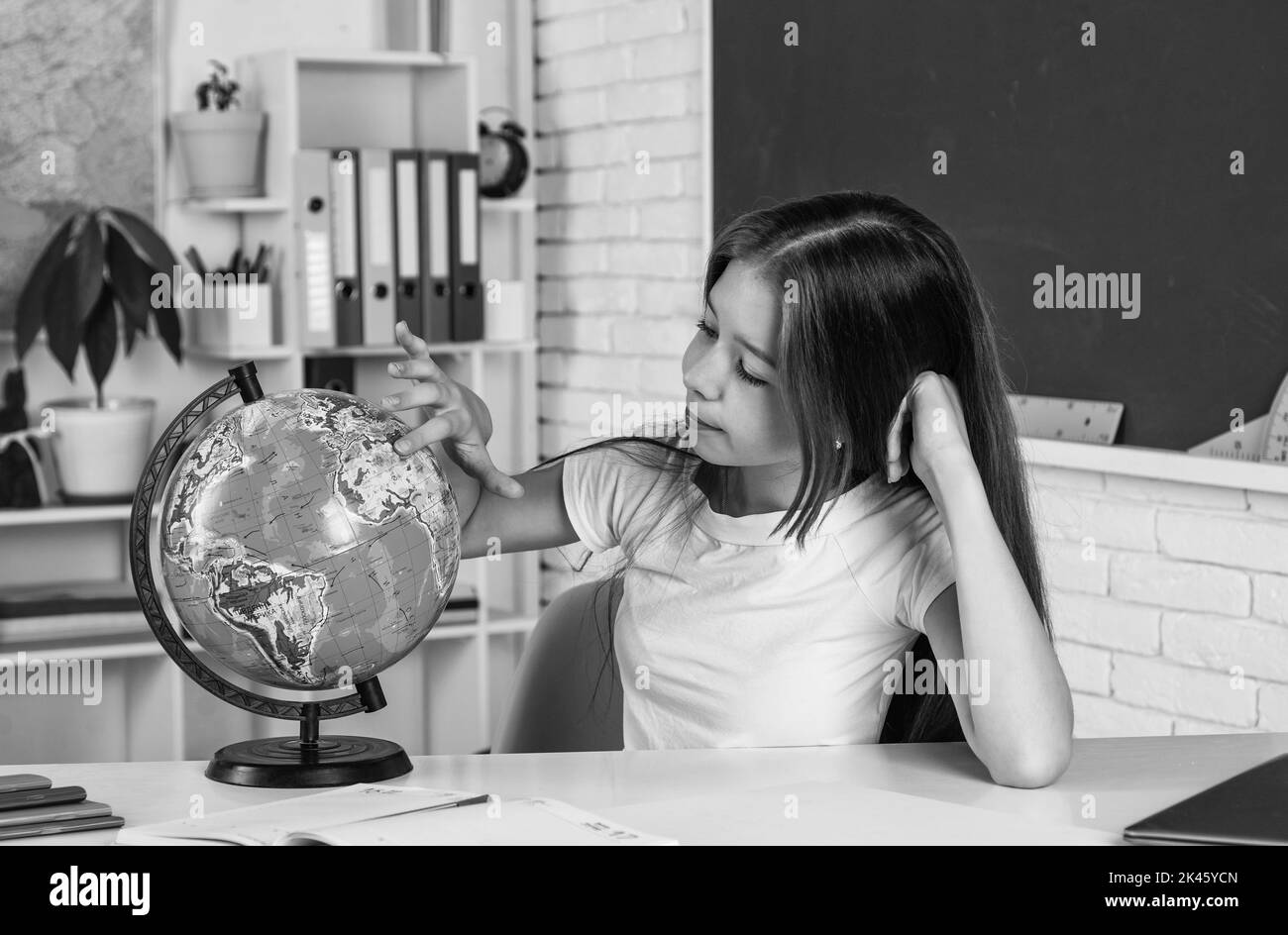 cheerful kid girl with globe at school lesson, geography Stock Photo