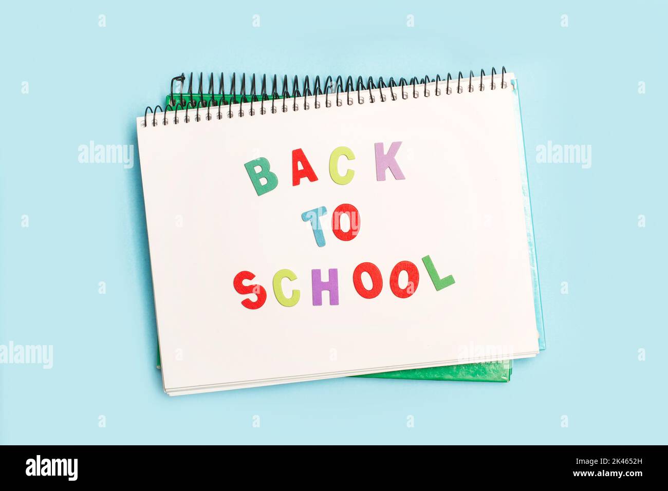 Back to school write in a notebook with colored toy wooden letters on a light blue background Stock Photo