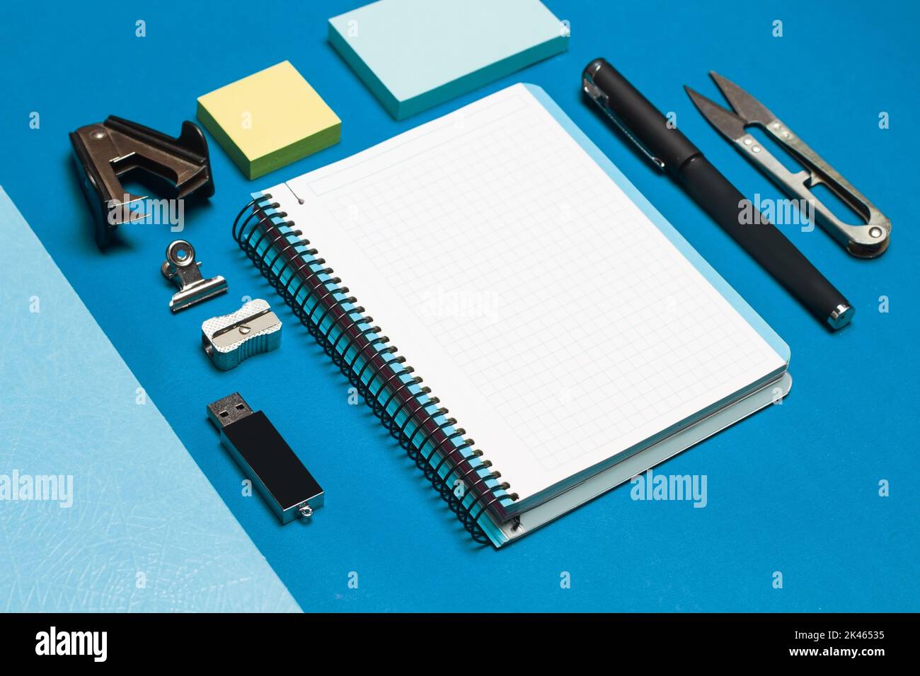 Open graph paper notebook and student utensils on a blue background Stock Photo