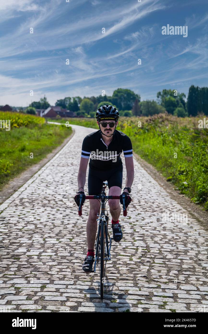 Male road cyclist on the famous sector of Pont Gibus from the classic Paris - Roubaix cycle race, municipality of Wallers in Northern France Stock Photo