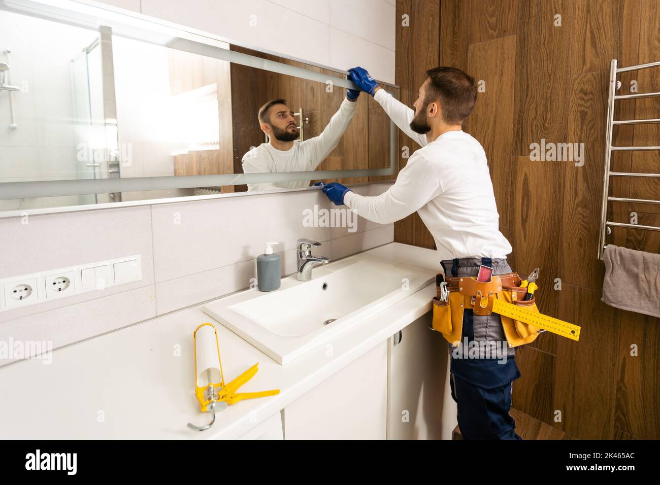 The worker installs the mirror in the bathroom Stock Photo Alamy