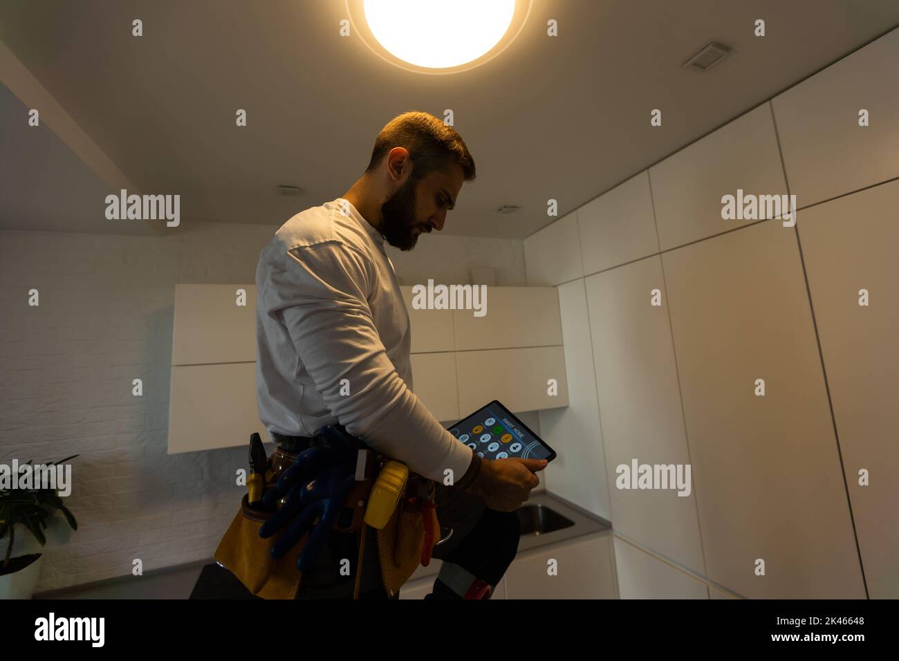 Installation lighting. Builder is holding a tablet in his hands. Concept - lighting engineer. Process installing. Electrician Stock Photo