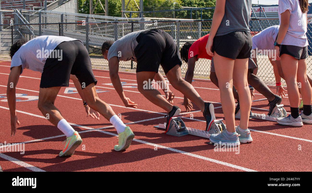 High school track runners starting a sprint race from the blocks at