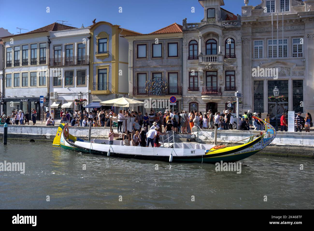 Aveiro, Portugal - August 14, 2022: Tourists disembarking from and queuing to embark a moored gondola with colonial style buildings in background Stock Photo