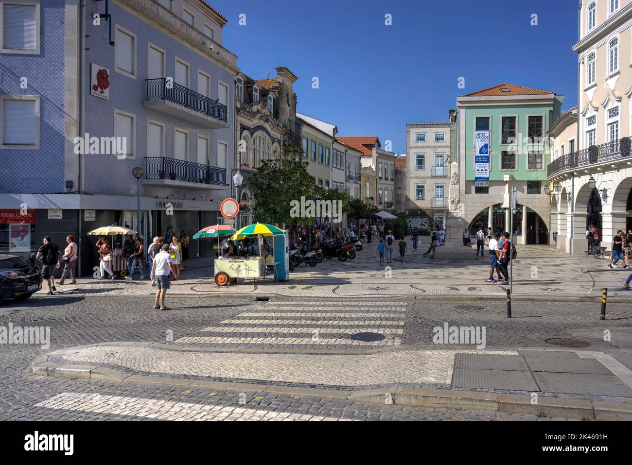 Aveiro, Portugal - August 14, 2022: Street scene with numerous motion blurred pedestrians and parked motor scooters with cobble-stoned road and crossw Stock Photo