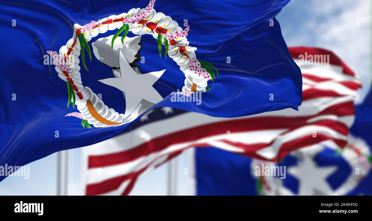 Flags of Northern Mariana Islands waving in the wind with the US flag on a clear day. The Northern Mariana Islands are an unincorporated territory and Stock Photo