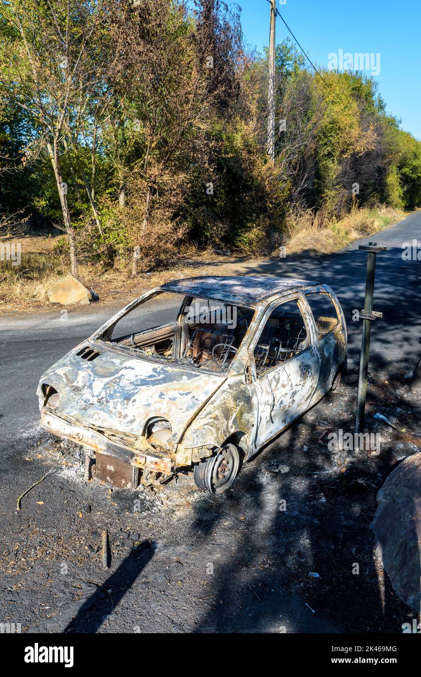 A city car burned out in a discreet street of a sensitive neighborhood. Stock Photo