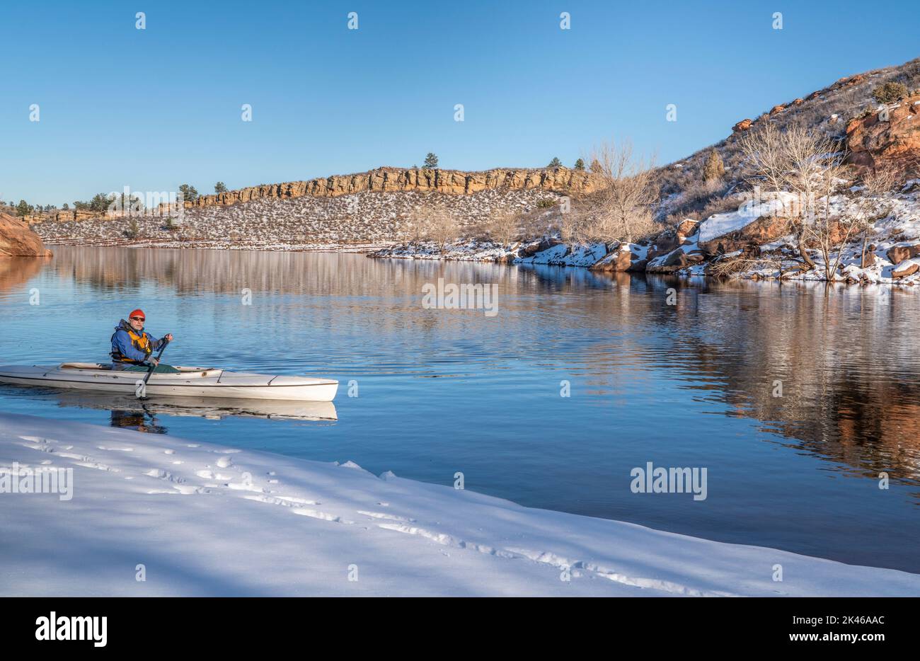 senior male wearing life jacket is paddling expedition canoe in winter scenery of Horsetooth Reservoir in northern Colorado Stock Photo