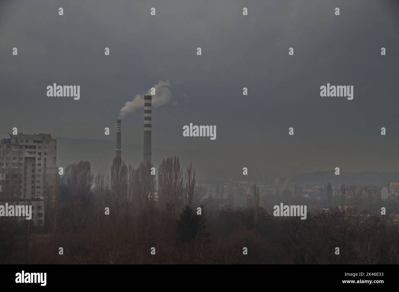 View of a gloomy winter day with fallen leaves from deciduous trees in a residential area against the background of the working chimneys of the Sofia Stock Photo