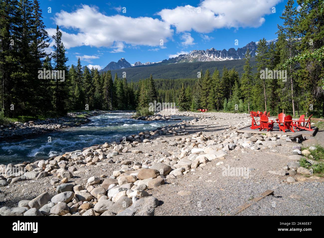 Red adirondack chairs near a creek along the Bow Valley Parkway in Banff National Park Canada Stock Photo