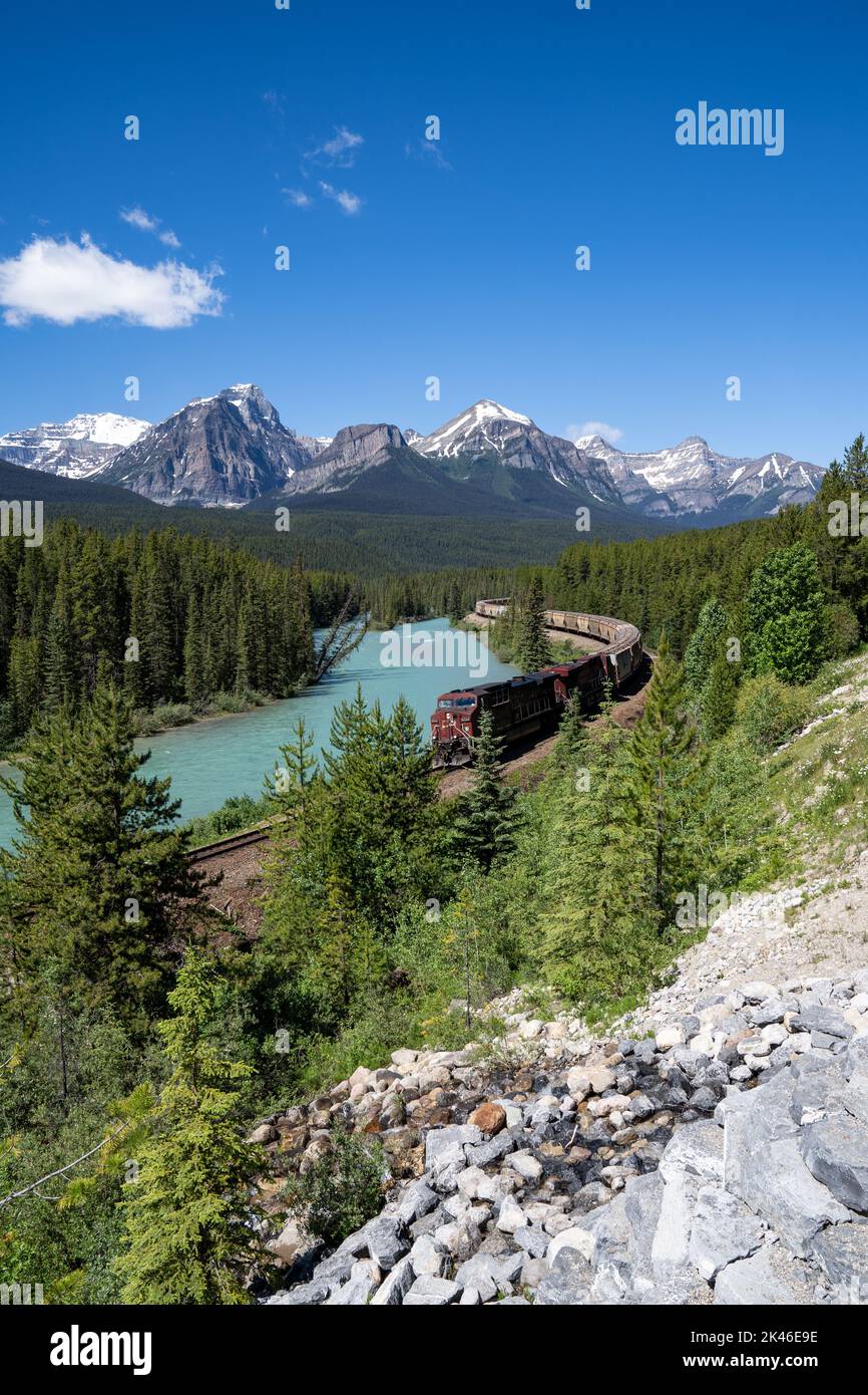 Train snakes its way through Morant's Curve in Banff National Park during summer Stock Photo