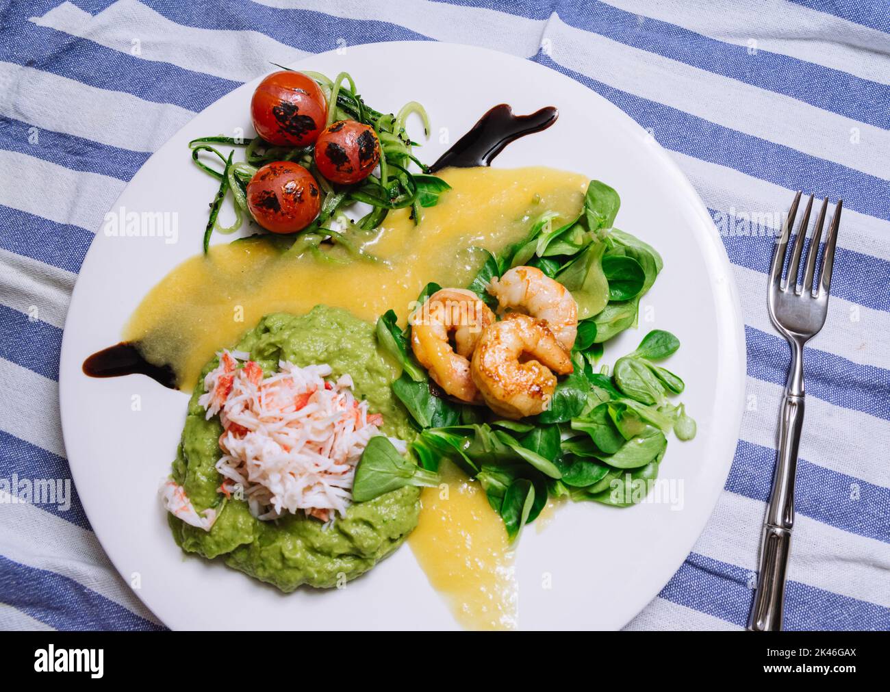 Salad with crab, cucumber, cocktail shrimp, avocado tartar and mango sauce. View from slightly above. Fresh and juicy foods. Homemade mouthwatering fo Stock Photo