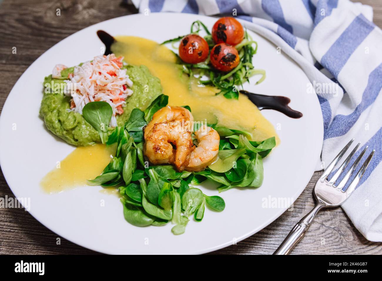 Salad with crab, cucumber, cocktail shrimp, avocado tartar and mango sauce. View from slightly above. Fresh and juicy foods. Homemade mouthwatering fo Stock Photo