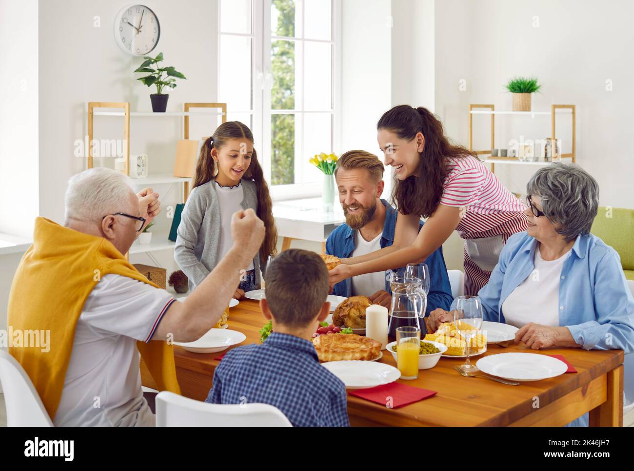 Happy cheerful family sitting around table at home and enjoying family meal together Stock Photo