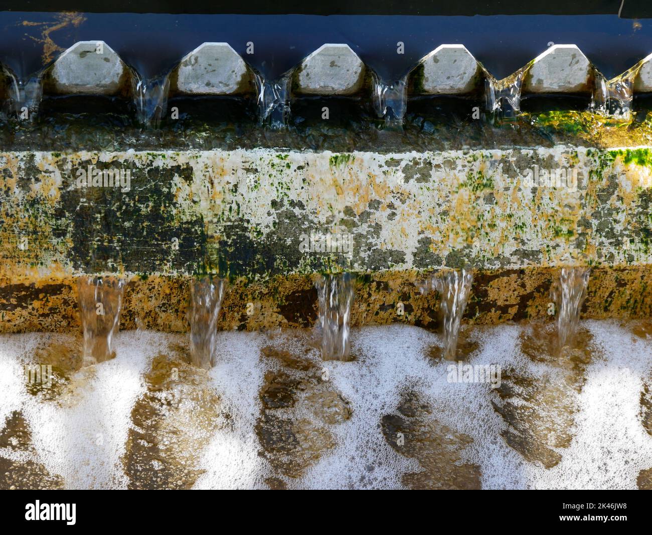 Treated water flowing thru a weir in a secondary trank in a waste water treatment plant Stock