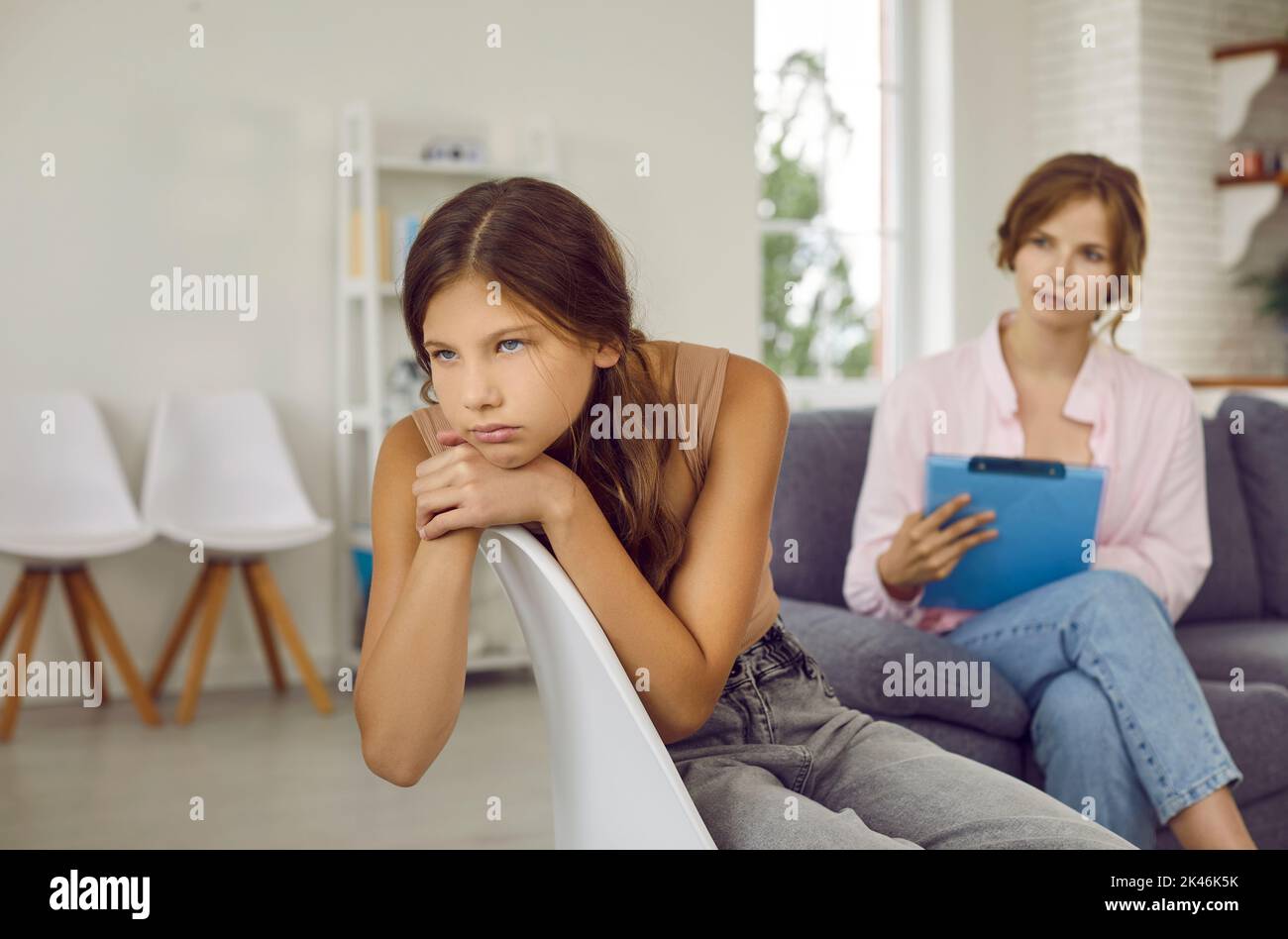 Sad teenage girl does not want to talk about problems and refuses to talk to psychologist. Stock Photo