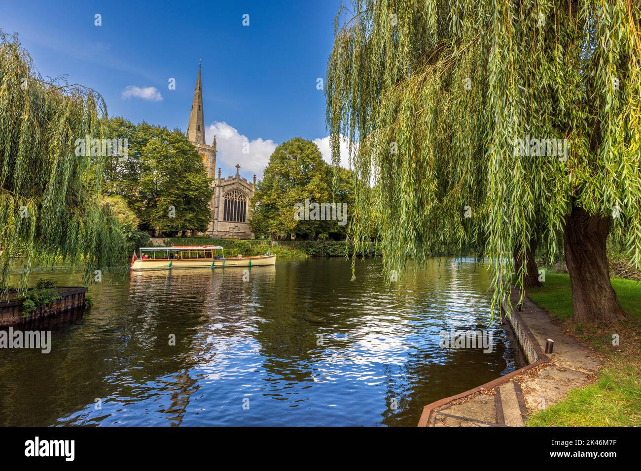 A River Cruise boat and Holy Trinity church across the river at Stratford Upon Avon, Warwickshire, England Stock Photo