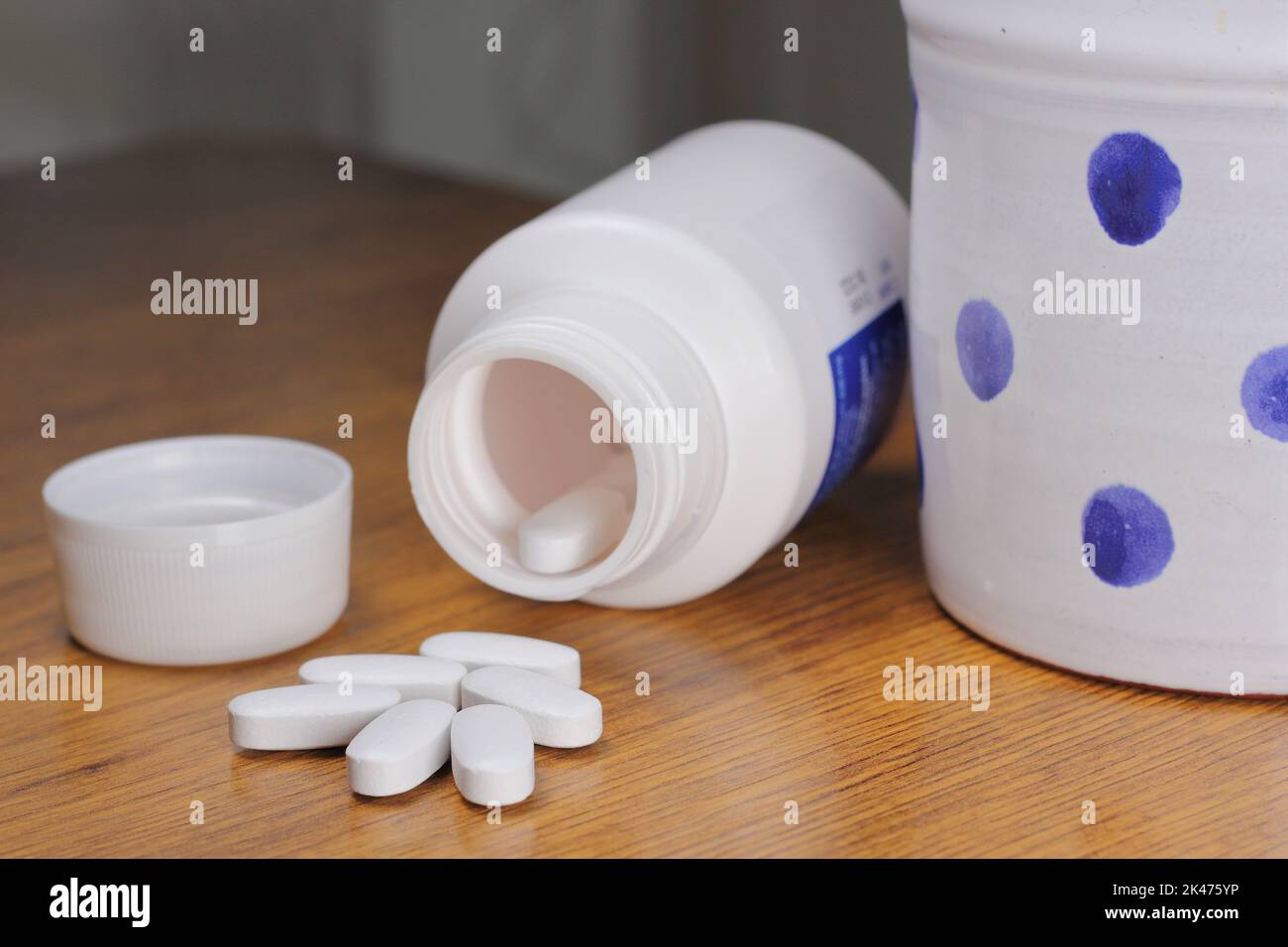 Anti-Radiation Pills, Iodine tablets, and tablets for radiation protection on the wooden table with a white medical jar and blue polka dot mug Stock Photo