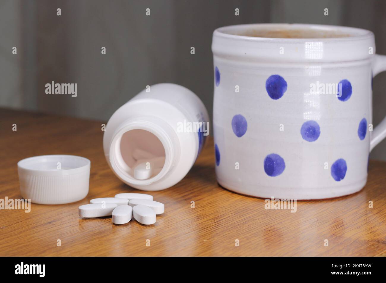 Anti-Radiation Pills, Iodine tablets, and tablets for radiation protection on the wooden table with a white medical jar and blue polka dot mug Stock Photo