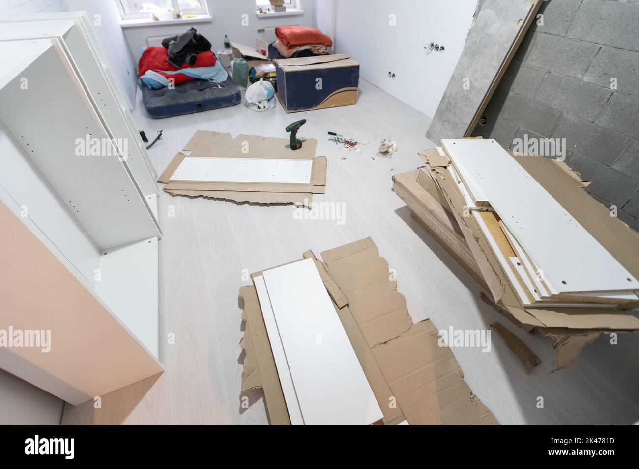 Parts of unfinished furniture, metal screws and tools lying on the ...