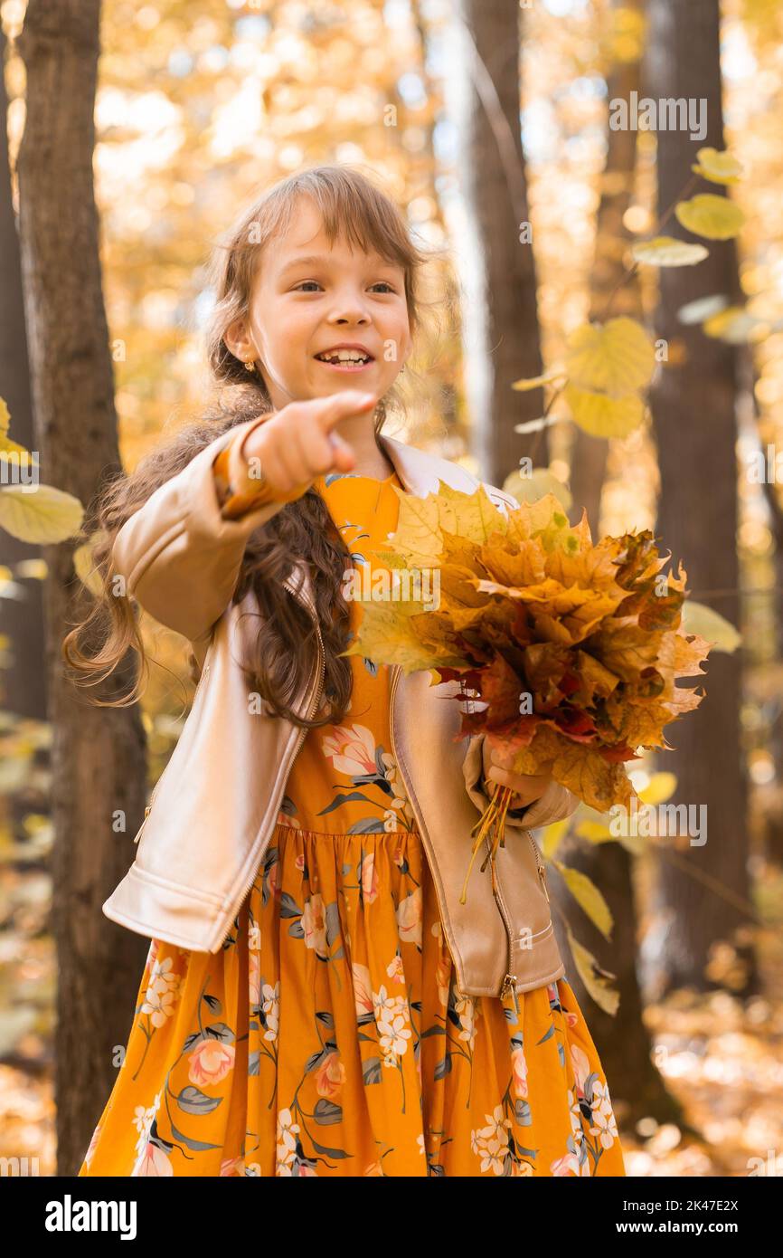 Little kid girl with autumn orange leaves in a park. Lifestyle, fall ...
