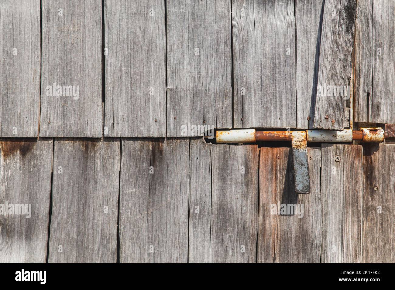 Rusty door bolt in old unpainted doors Stock Photo