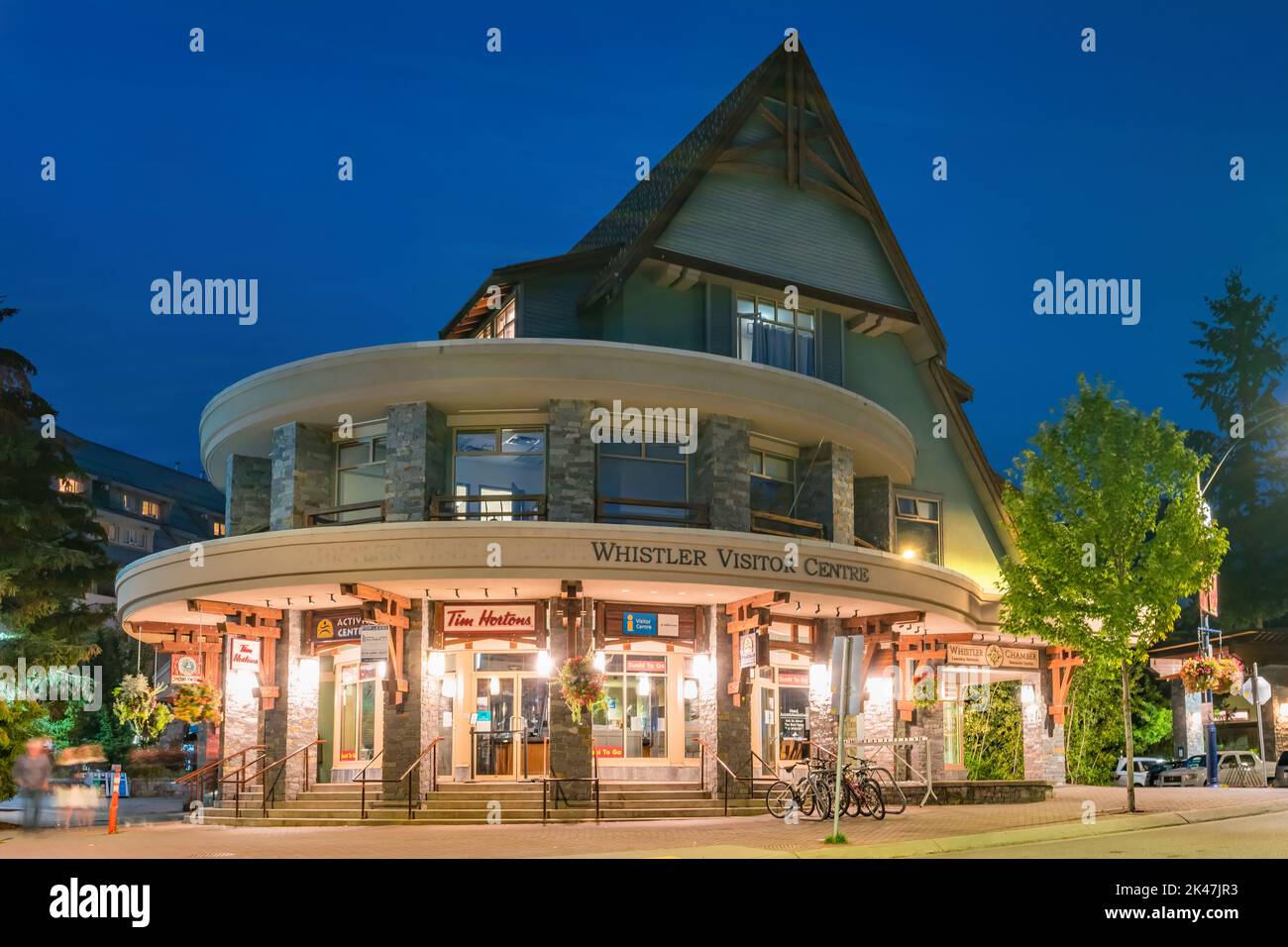Pedestrians walk past the Visitor Centre in Whistler Village, BC, Canada at night. Stock Photo