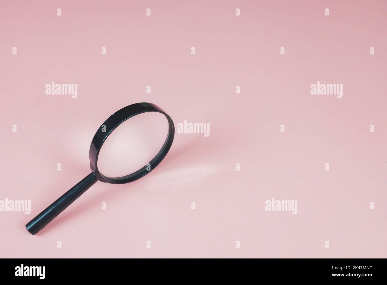 Magnifying glass on the pink background. Light is refracted through glass of magnifier. Copy space for text. Finding and zooming concept. Lens, loupe. Stock Photo