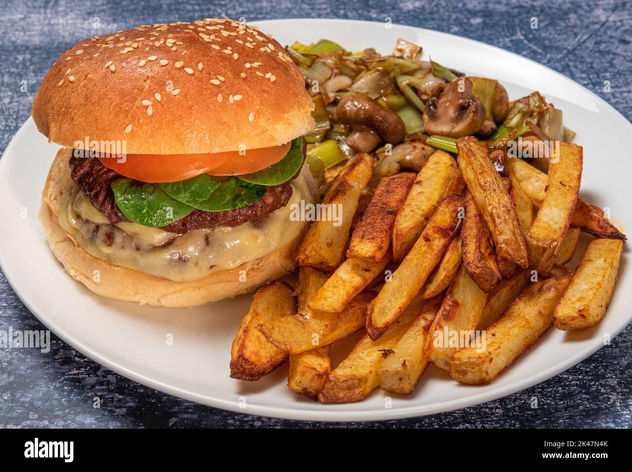 Beefburger in brioche burger bun with home made skin on chips and mushrooms Stock Photo