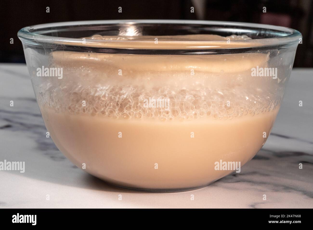 fermenting bread yeast in glass bowl from side Stock Photo