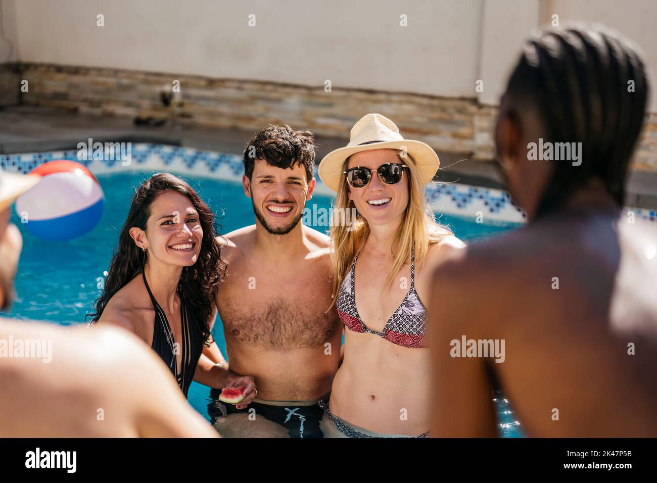 portrait of young latin man with 2 women inside a swimming pool Stock Photo