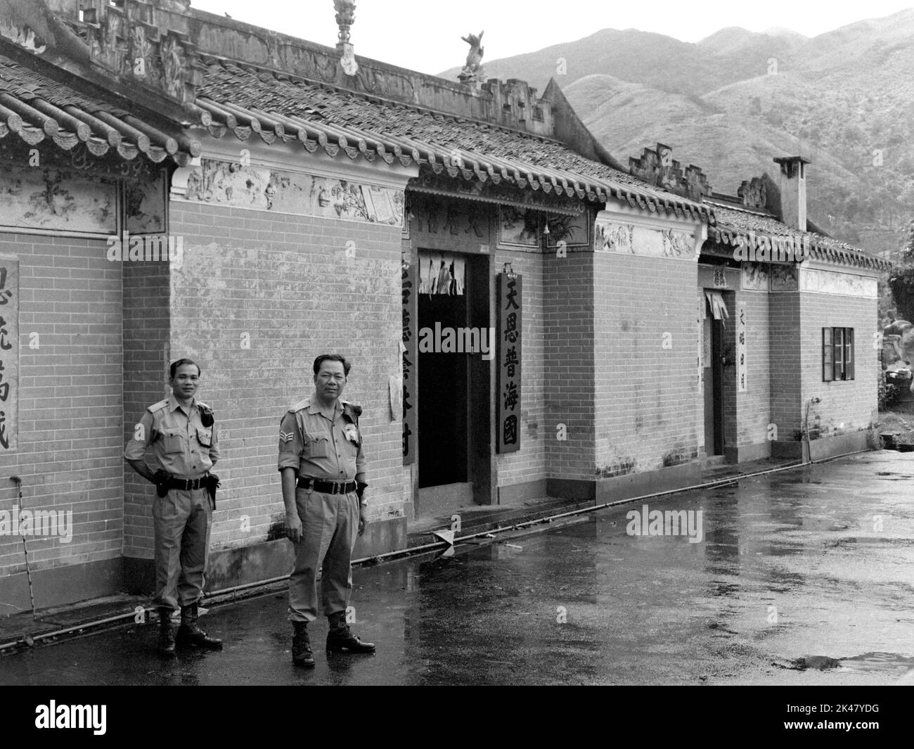 Outside the Tin Hau Temple at Fong Ma Po village, two policemen from the 'Lam Tsuen Rural Patrol Unit', Tai Po Division, Royal Hong Kong Police, Hong Kong summer 1984. Stock Photo