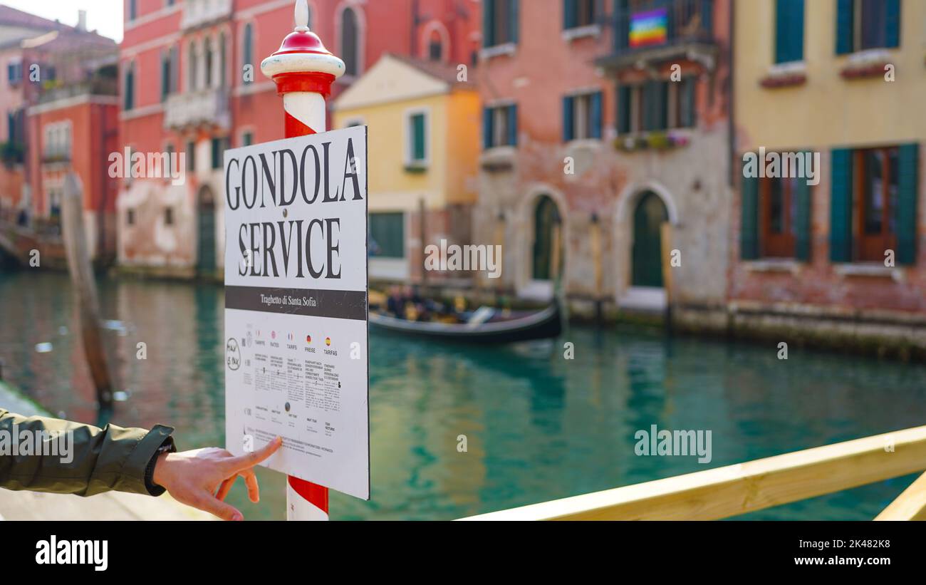 A person pointing at a gondola service sign in Venice Stock Photo