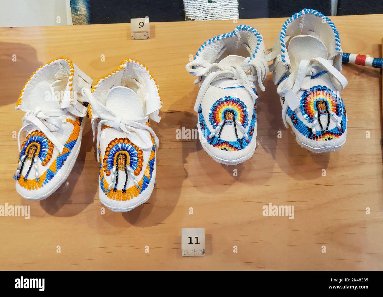 Two pair of white leather children's moccasins, piischui nuupacha, with beaded warrior in headdress. On display at the Museum of Northern Arizona in F Stock Photo