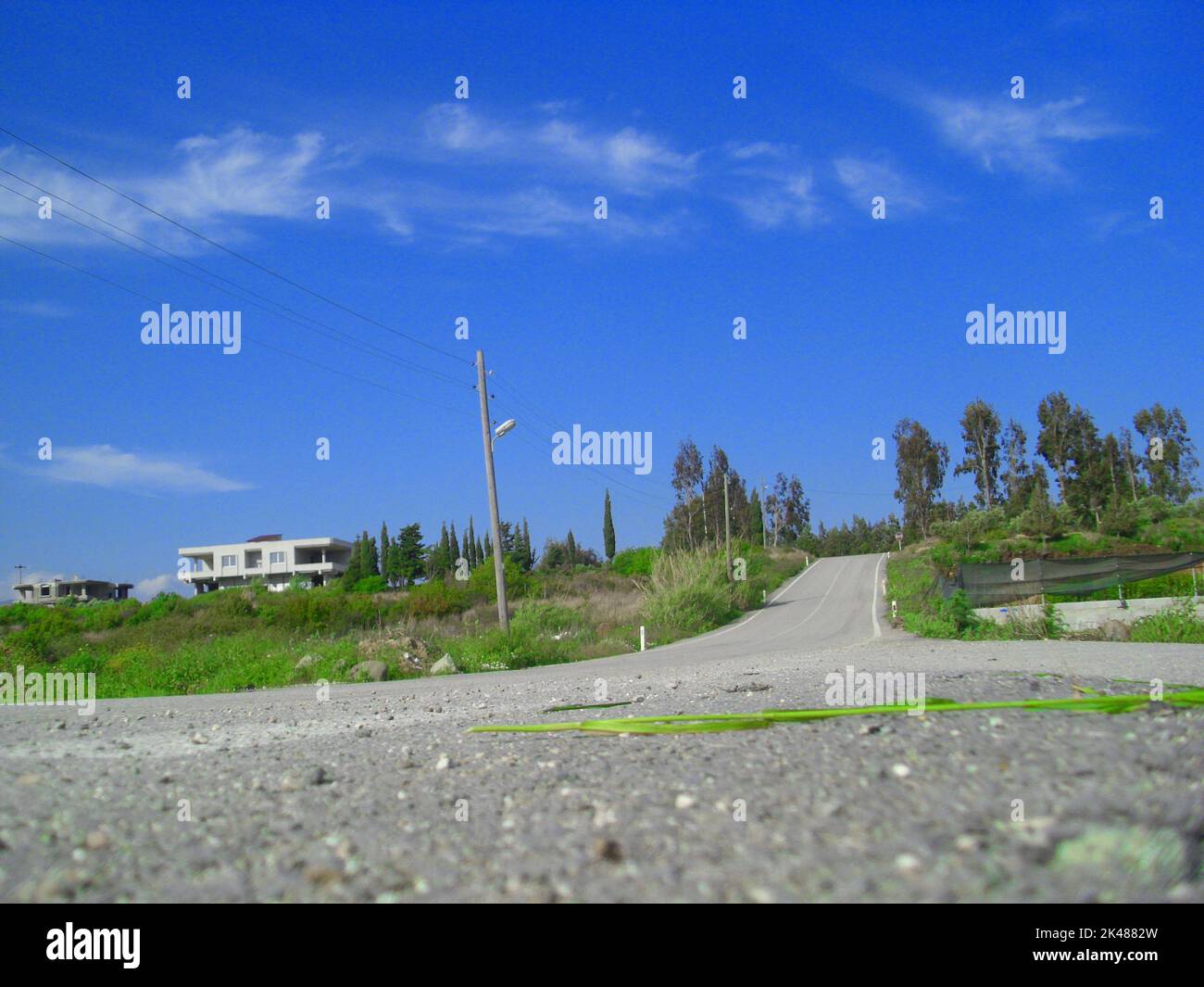 Slope road low angle shoot. View of village in green and blue sky Stock