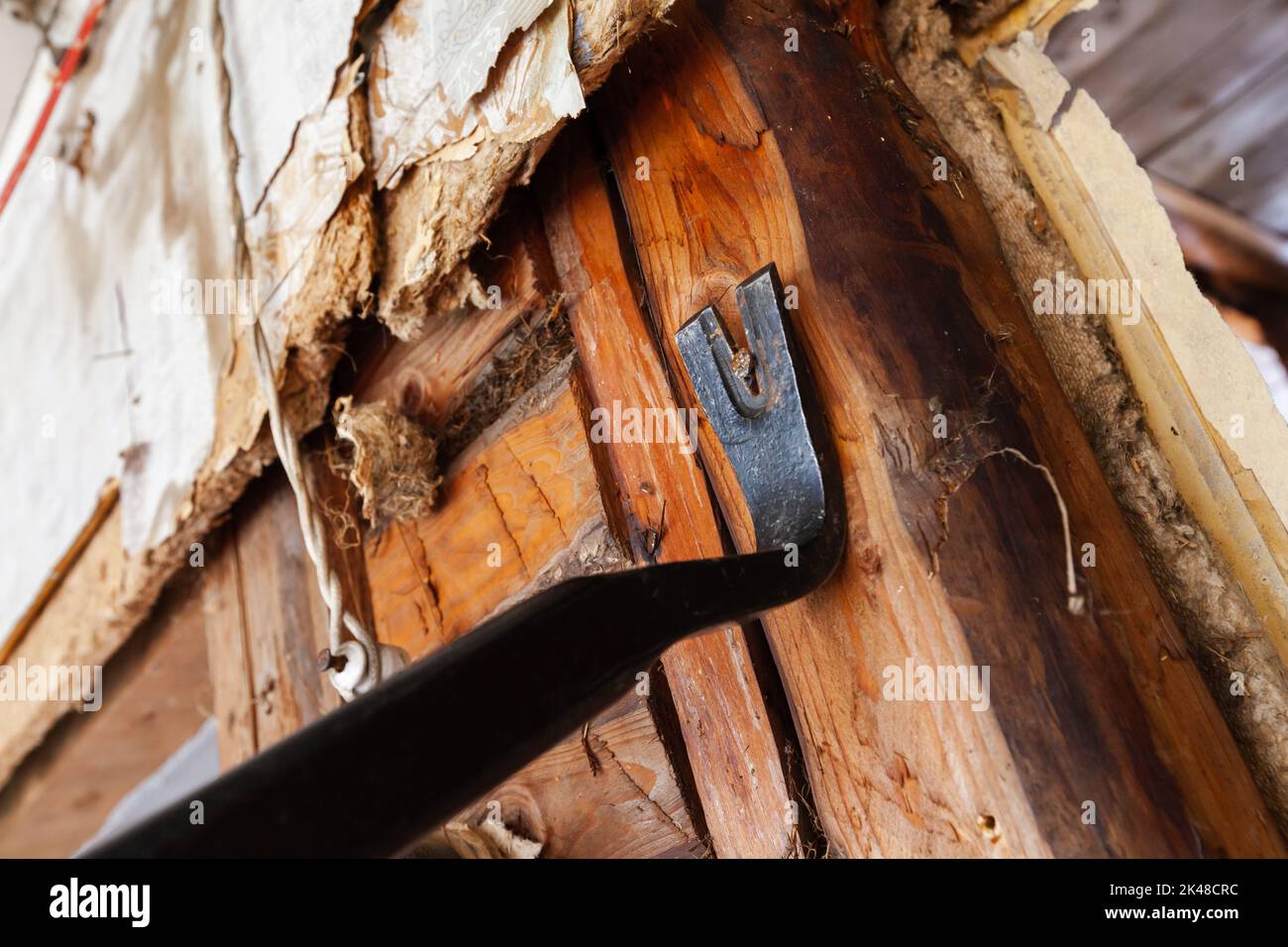 Black nail puller removes a nail out of old wooden wall Stock Photo