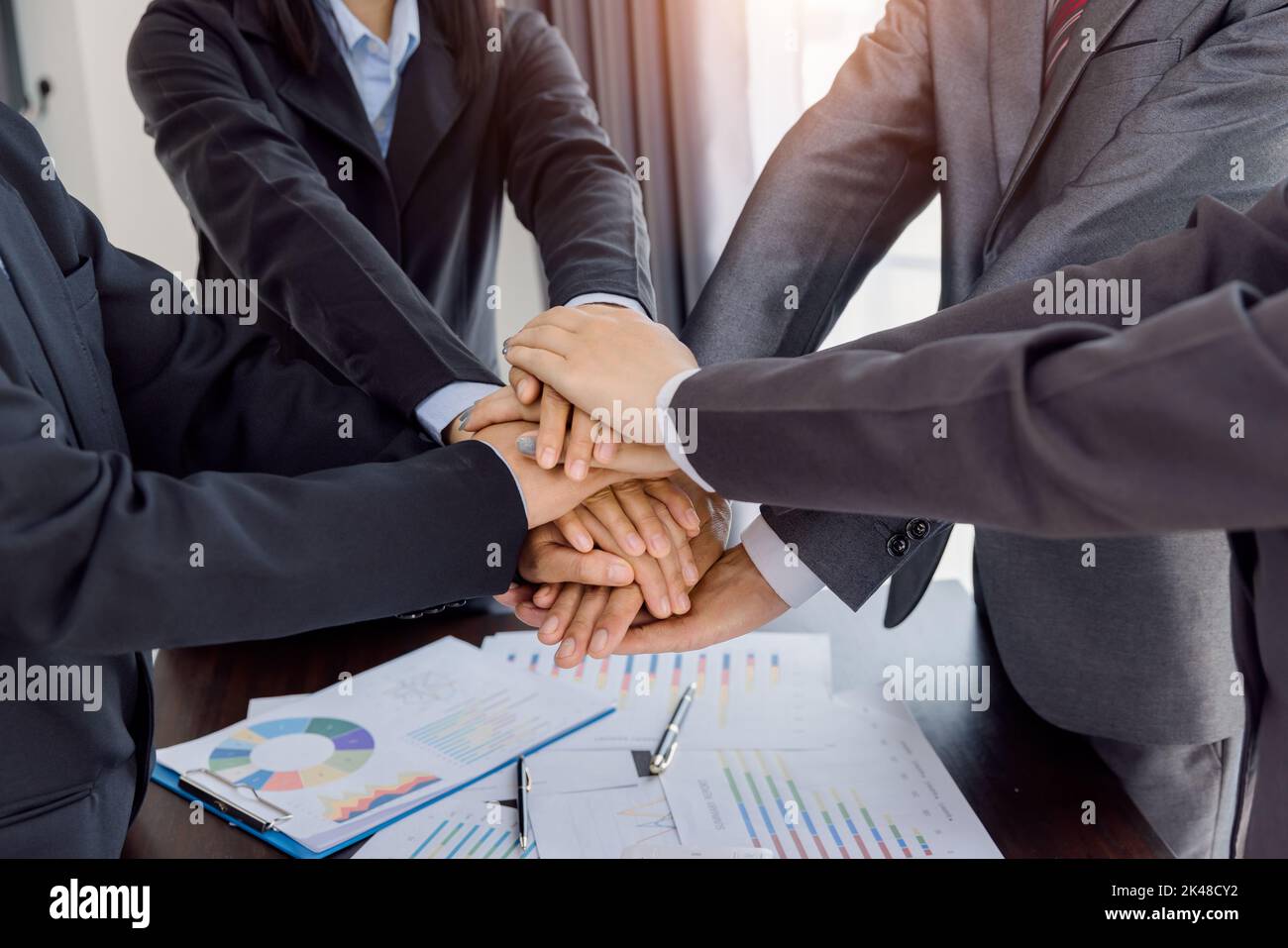 Businesspeople holding joined hands above desk with gadgets, Teamwork ...