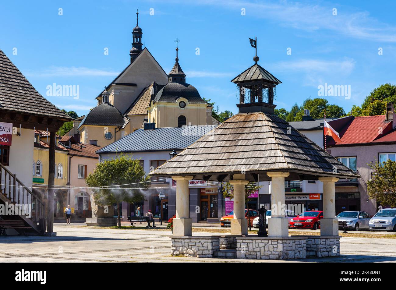 Pilica, Poland - July 25, 2022: Historic renewed wooden well aside Town Hall Ratusz Miejski at Rynek Main Market square in old town quarter of Pilica Stock Photo