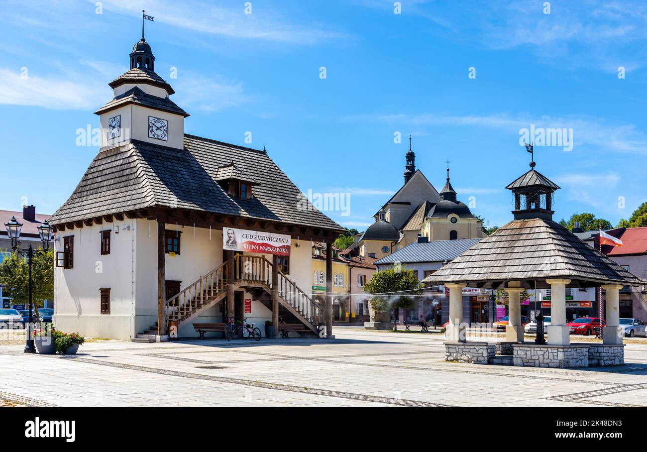 Pilica, Poland - July 25, 2022: Historic Town Hall Ratusz Miejski and renewed wooden well at Rynek Main Market square in old town quarter of Pilica Stock Photo