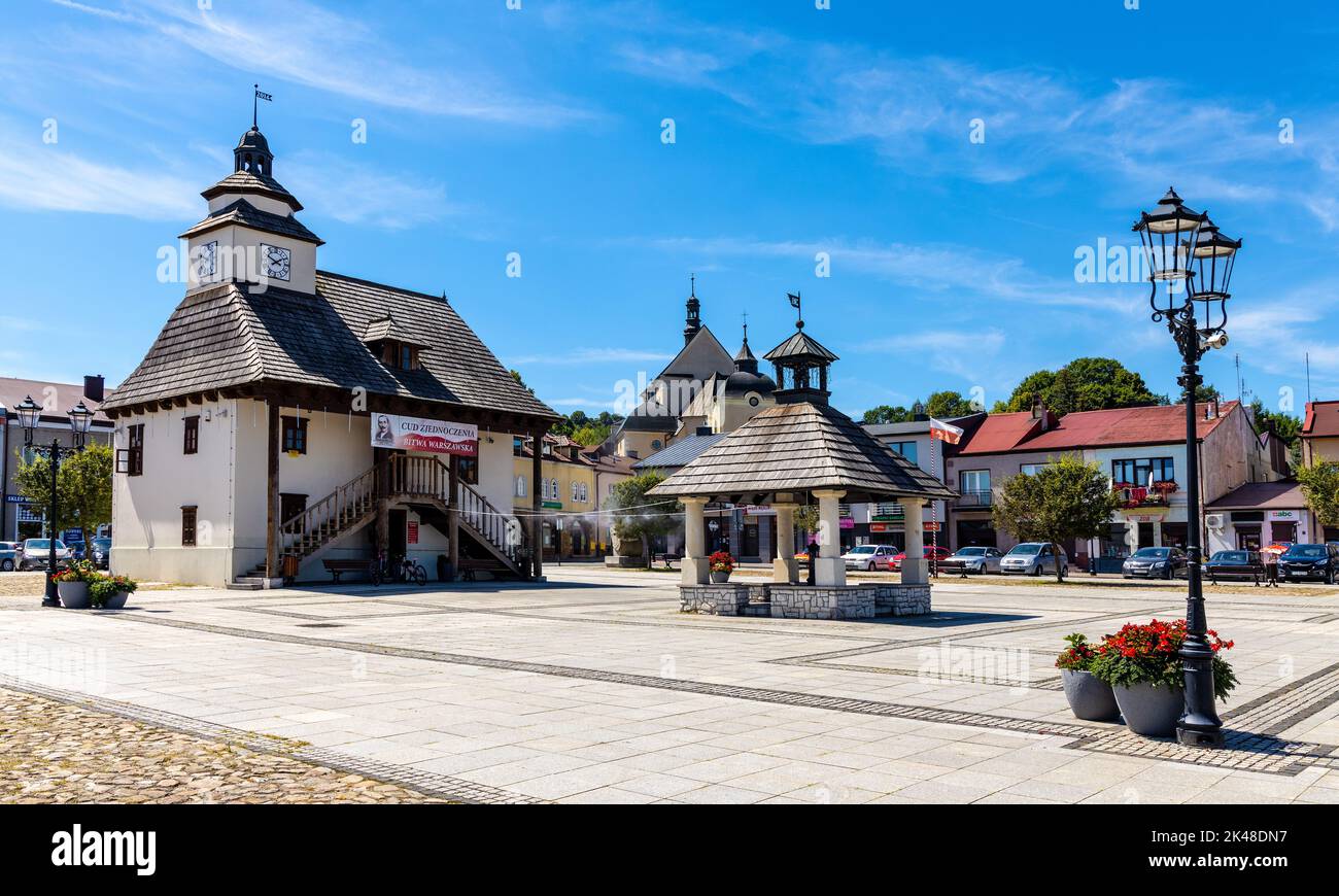 Pilica, Poland - July 25, 2022: Historic Town Hall Ratusz Miejski and renewed wooden well at Rynek Main Market square in old town quarter of Pilica Stock Photo