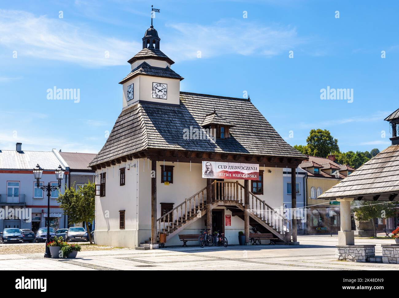 Pilica, Poland - July 25, 2022: Historic Town Hall Ratusz Miejski and renewed wooden well at Rynek Main Market square in old town quarter of Pilica Stock Photo