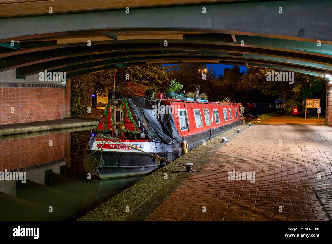 Canal boats moored under a bridge on the Oxford canal in Banbury at dawn. Castle Quay Waterfront. Banbury, Oxfordshire, England Stock Photo