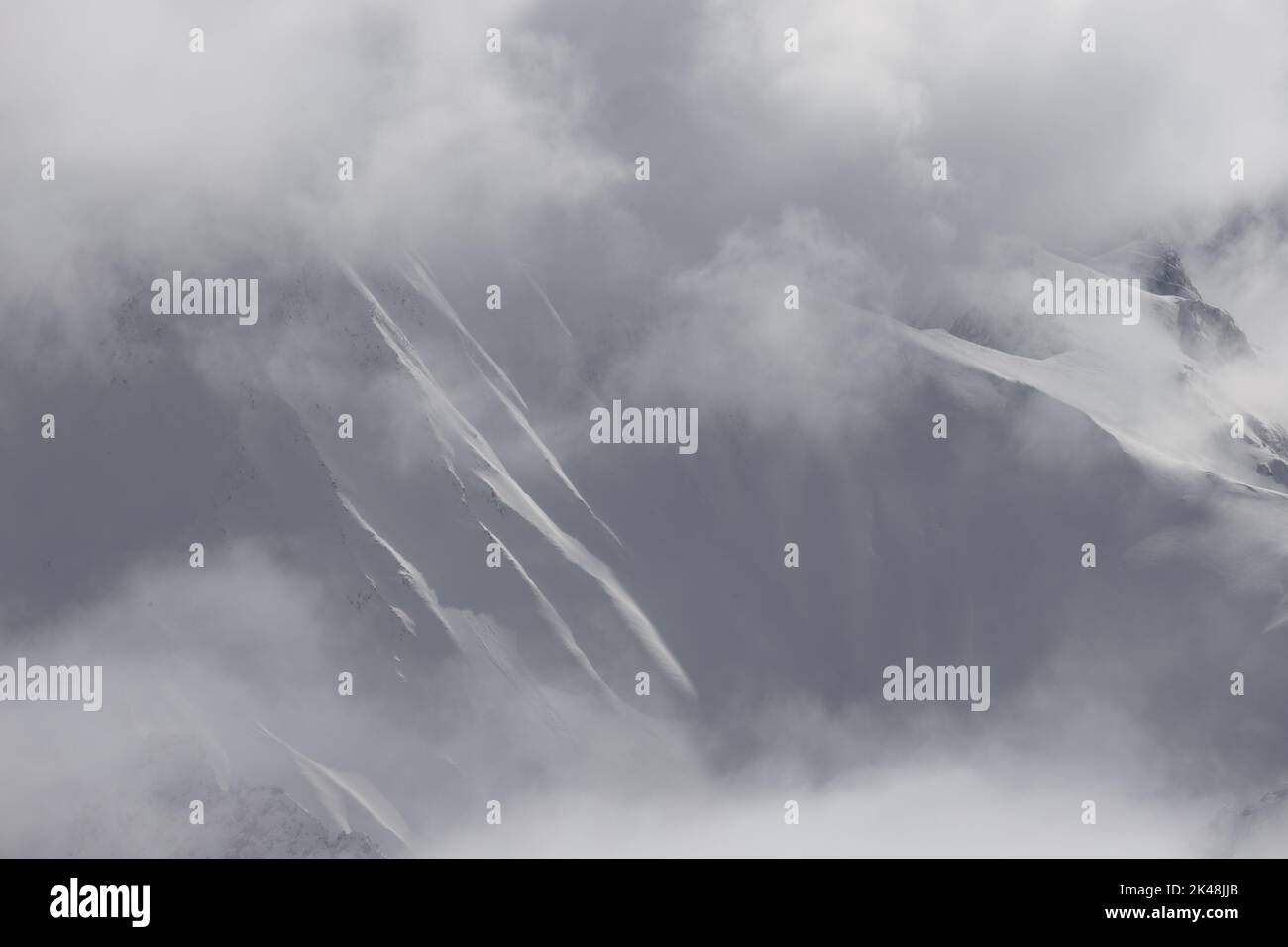 Von der Zugspitze aus hat man auch bei Nebel und Wolken spannende Aussichten auf die Alpengipfel. Besonders im Winter öffnen sich atemberaubende Ausblicke auf die Bergwelt der Alpen. Hier sieht man die schneebedeckten Konturen am Gipfel der Zugspitze. Stock Photo