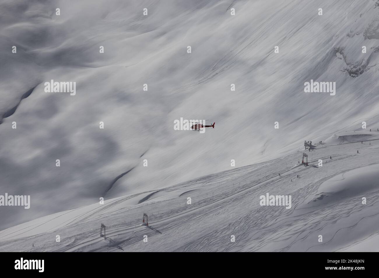 Ein Rettungshubschrauber schwebt auf eine Unfallstelle. Ein Skiläufer ist gestürzt und braucht dringend medizinische Hilfe. Im Neuschnee gibt es noch keine Spuren. Stock Photo