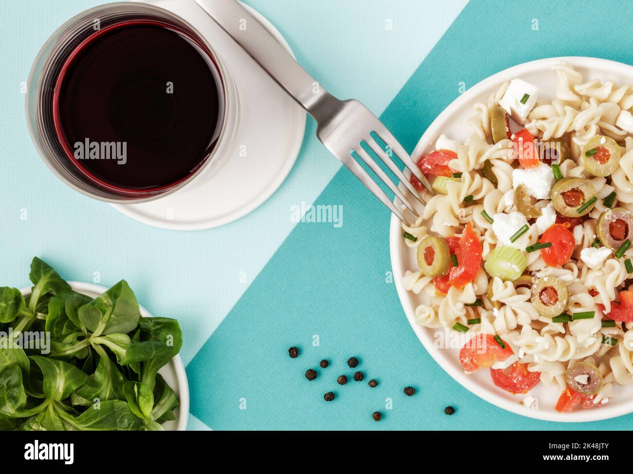 Spelt pasta spirals salad and a glass of red wine Stock Photo