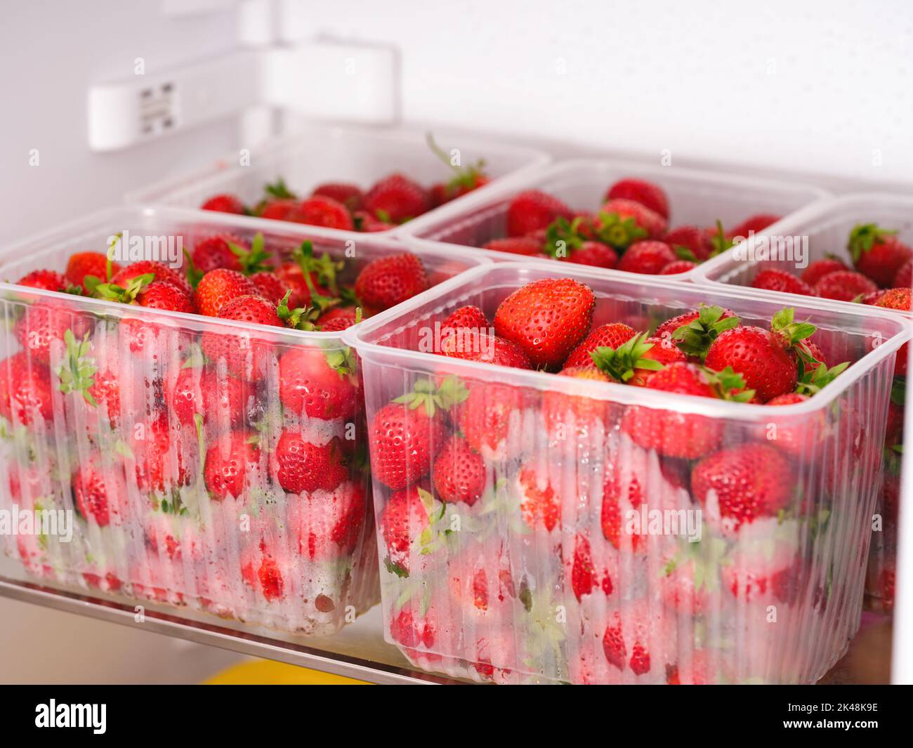 Five plastic containers with organic red strawberries in them in a refrigerator Stock Photo